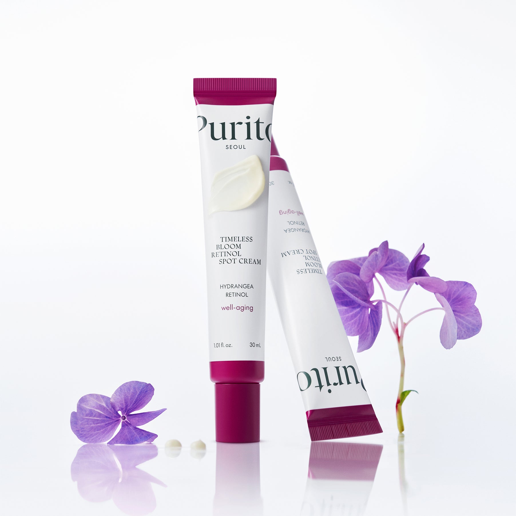 Décris l'image en français : PURITO Timeless Bloom Retinol Spot Cream 30ml, crème anti-taches PURITO sur fond blanc, fleurs violettes.
