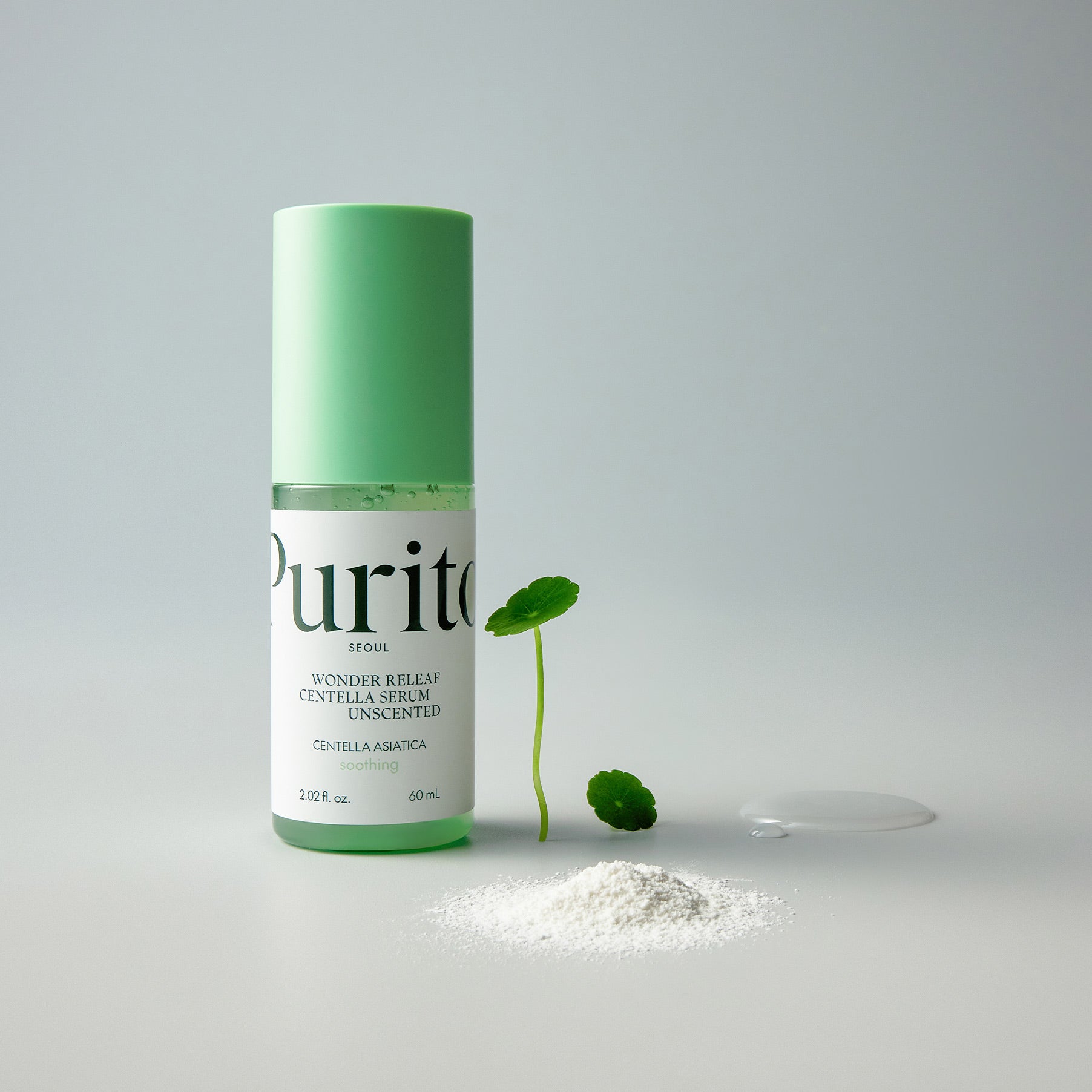 PURITO Wonder Releaf Centella Serum Unscented 60ml, flacon vert et gouttes sur fond clair avec feuilles de centella.