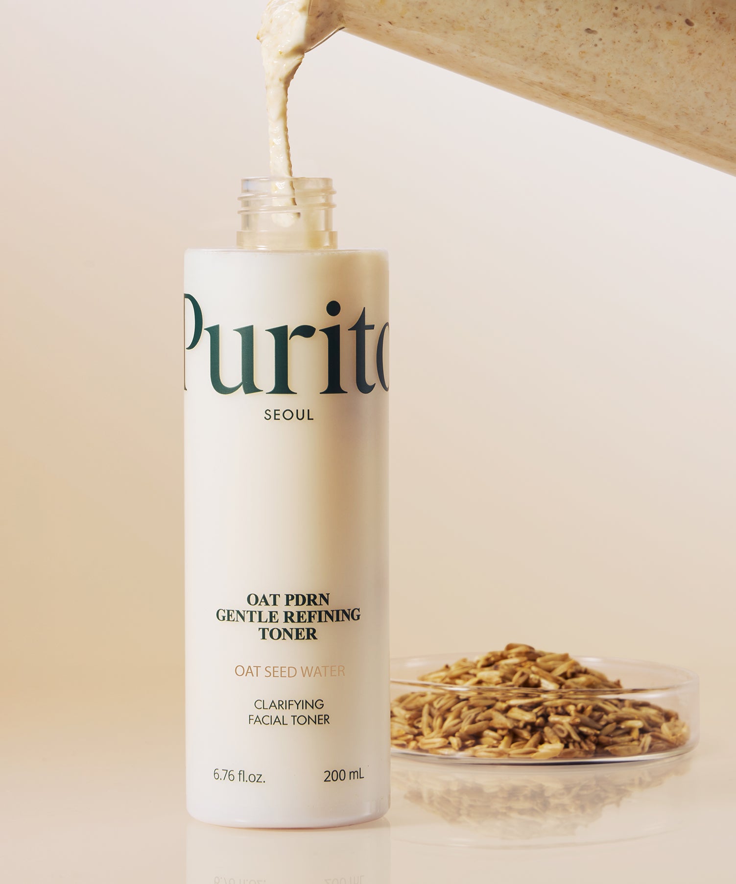 PURITO Oat PDRN Gentle Refining Toner 200ml sur fond de grains d'avoine, flacon ouvert et liquide crémeux s'écoulant. Soin du visage clarifiant.