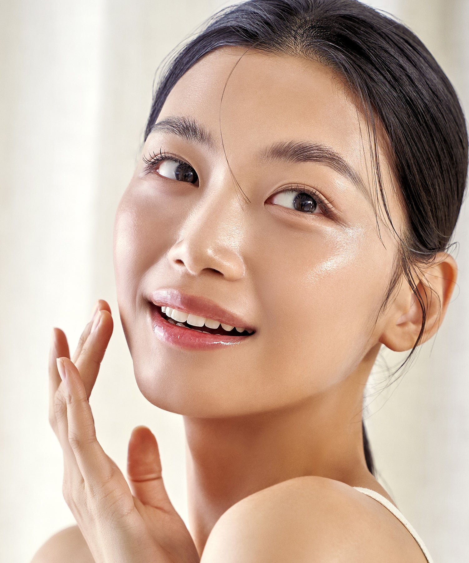 Femme souriante appliquant le PURITO Wonder Relief Centella Daily Sun Lotion SPF50+PA++++ pour une peau radieuse.