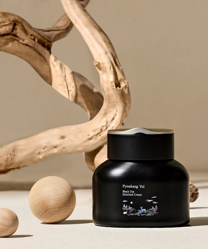 Crème enrichie PYUNKANG YUL Black Tea 60ml avec décor naturel en arrière-plan.
