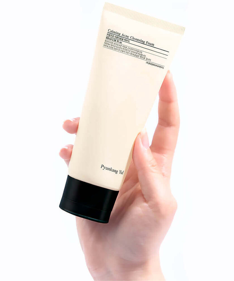Main tenant un tube de PYUNKANG YUL Calming Acne Cleansing Foam 100ml pour peau acnéique, produit soin visage.