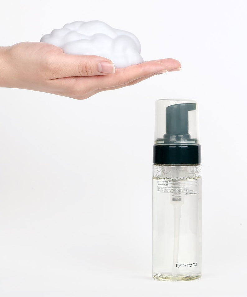 Main avec mousse devant PYUNKANG YUL Calming Low pH Foaming Cleanser 150ml en bouteille transparente.