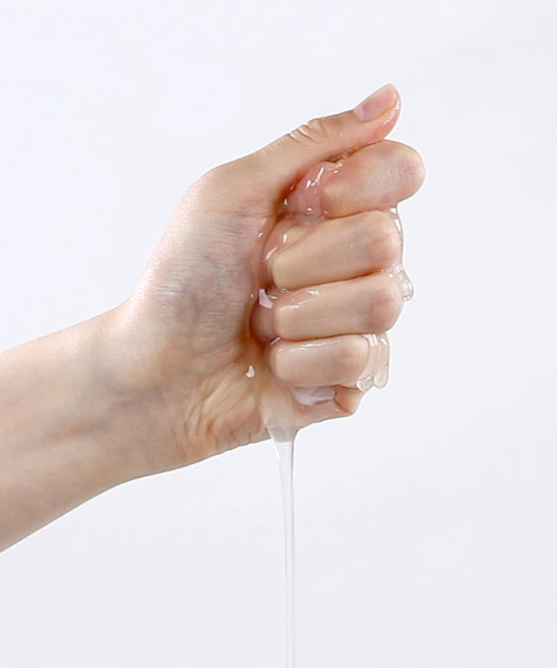 Main tenant le masque de la PYUNKANG YUL Calming Mask Pack 10 Pieces libérant son sérum apaisant en abondance.