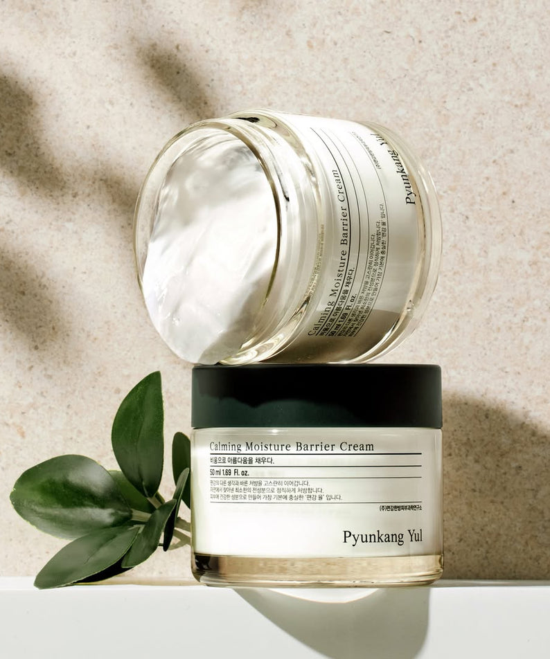 Crème apaisante PYUNKANG YUL Calming Moisture Nourishing Cream 50ml en pot ouvert avec plantes décoratives.