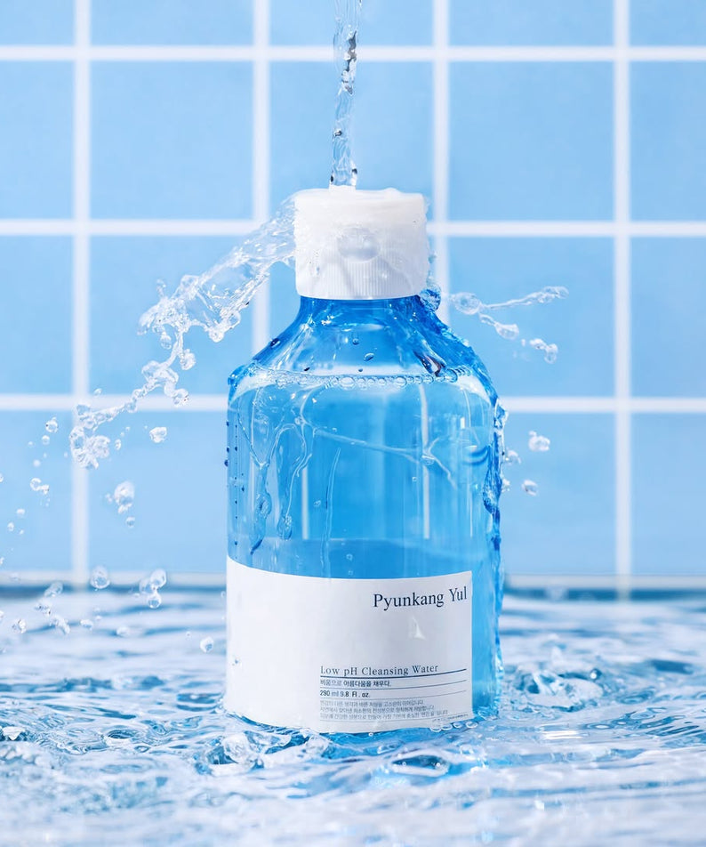 PYUNKANG YUL Mildly Acidic Cleansing Water 290ml éclaboussé d'eau dans une salle de bain bleue, capturant sa pureté rafraîchissante.
