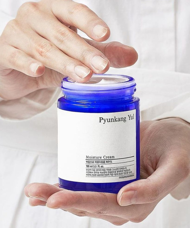 Crème hydratante PYUNKANG YUL Moisture Cream 100ml dans les mains, hydratation intense pour peau en bonne santé.