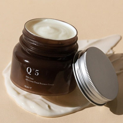 QUA-T Dia All Green Total Essence Cream 100ml QUA-T, pot brun ouvert sur fond beige, crème verte visible, style skincare