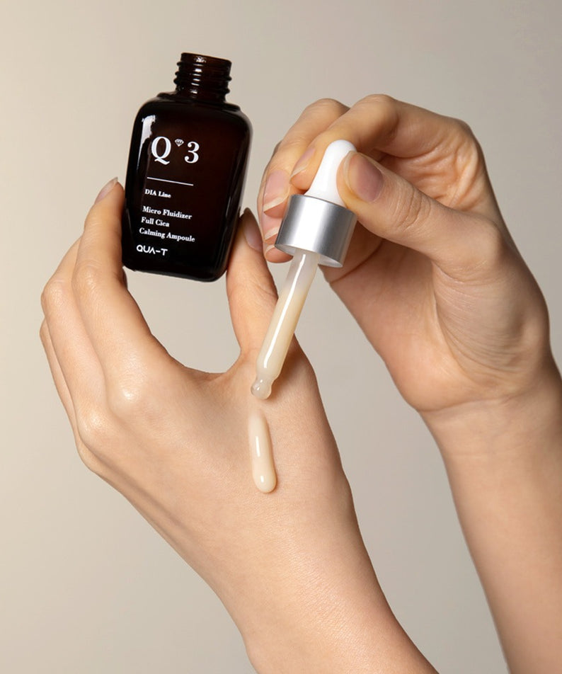 QUA-T Dia Nano Emulsion Full Cica Soothing Ampoule 30ml QUA-T, mains appliquant la texture apaisante, fond clair