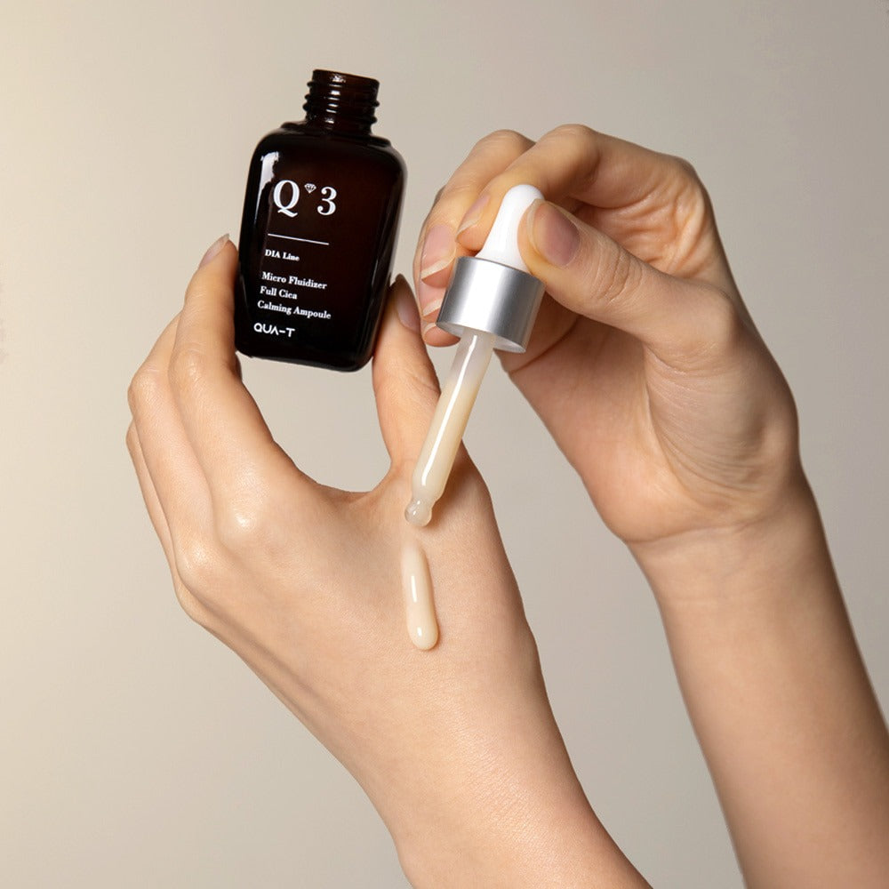 QUA-T Dia Nano Emulsion Full Cica Soothing Ampoule 30ml QUA-T, mains appliquant la texture apaisante, fond clair