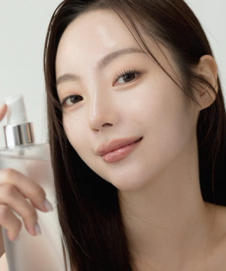 QUA-T Toner 200ml, marque QUA-T, présenté en cosmétique sur la main d’une femme, visage au premier plan.