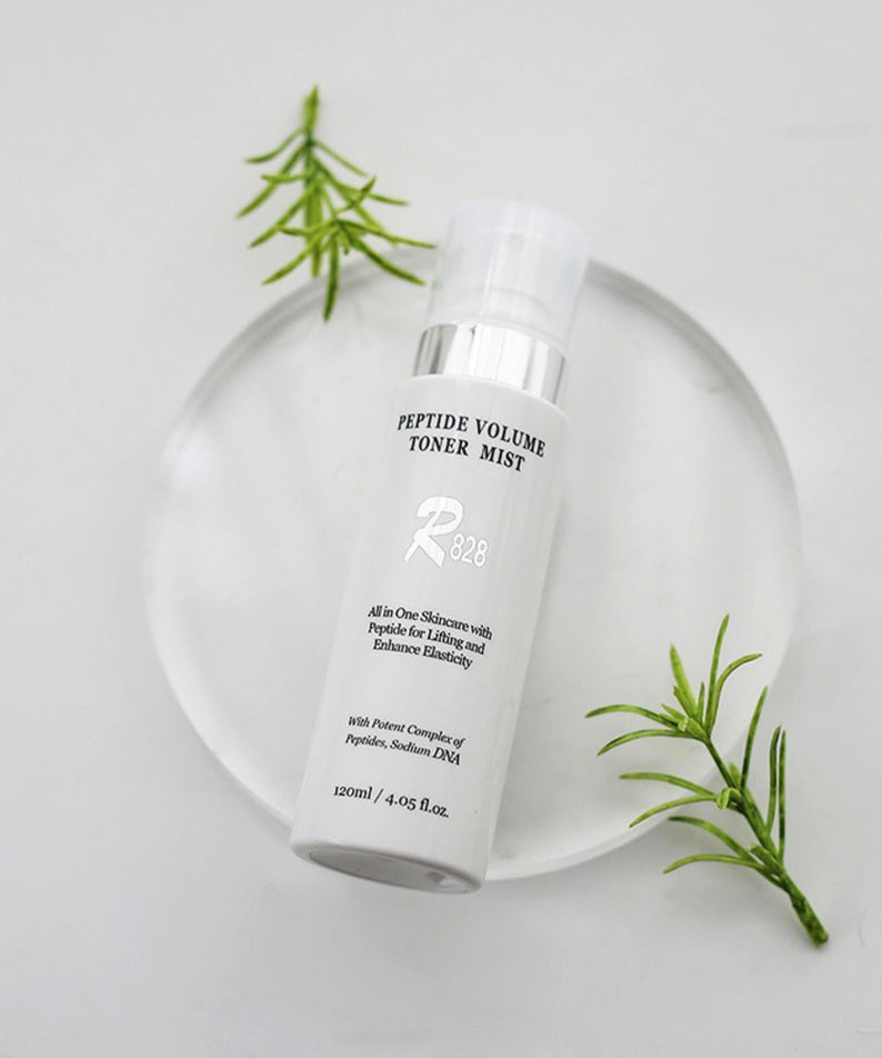 R828 Peptide Volume Toner Mist, flacon blanc sur fond clair, brins de romarin et vue produit en studio.