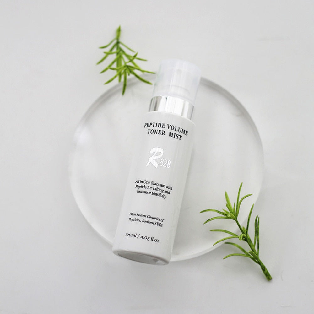 R828 Peptide Volume Toner Mist, flacon blanc sur fond clair, brins de romarin et vue produit en studio.