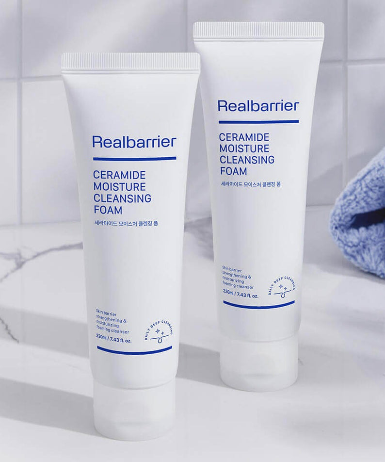 REAL BARRIER Ceramide Moisture Cleansing Foam 220ml Realbarrier, tubes blancs sur fond salle de bain avec serviette bleue.