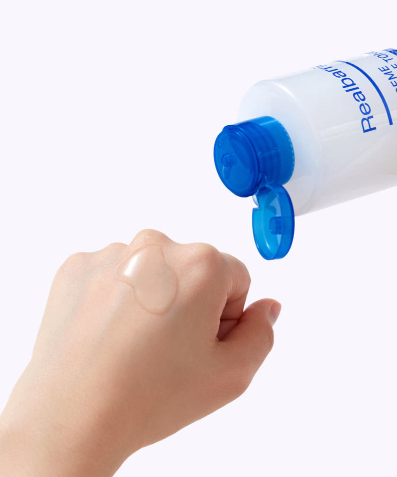REAL BARRIER Extreme Essence Toner Original 200ml de la marque, flacon blanc/bleu avec bouchon, main qui verse sur fond clair.