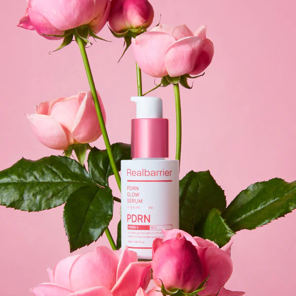 REAL BARRIER PDRN Radiance Repair Serum 30ml, flacon rose entre roses sur fond rose, marque Realbarrier, ambiance beauty.