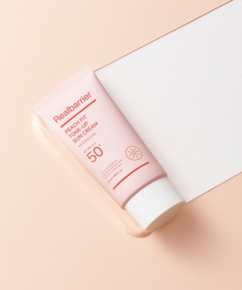 REAL BARRIER Peach Fit Tone-Up Sun Cream 50ml de la marque Real Barrier, tube crème solaire sur fond pastel beige.