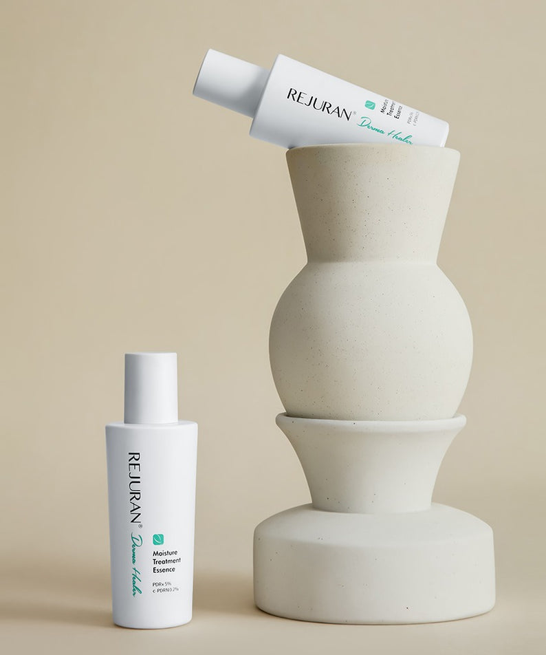 Décris l'image en français : REJURAN Derma Healer Moisture Treatment Essence 70g de la marque REJURAN, flacon sur fond beige.