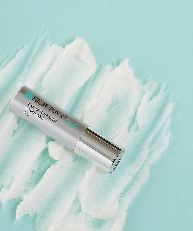 REJURAN Healer Calming Lip Balm 3.7g sur fond turquoise avec texture apaisante, hydrate et protège les lèvres.