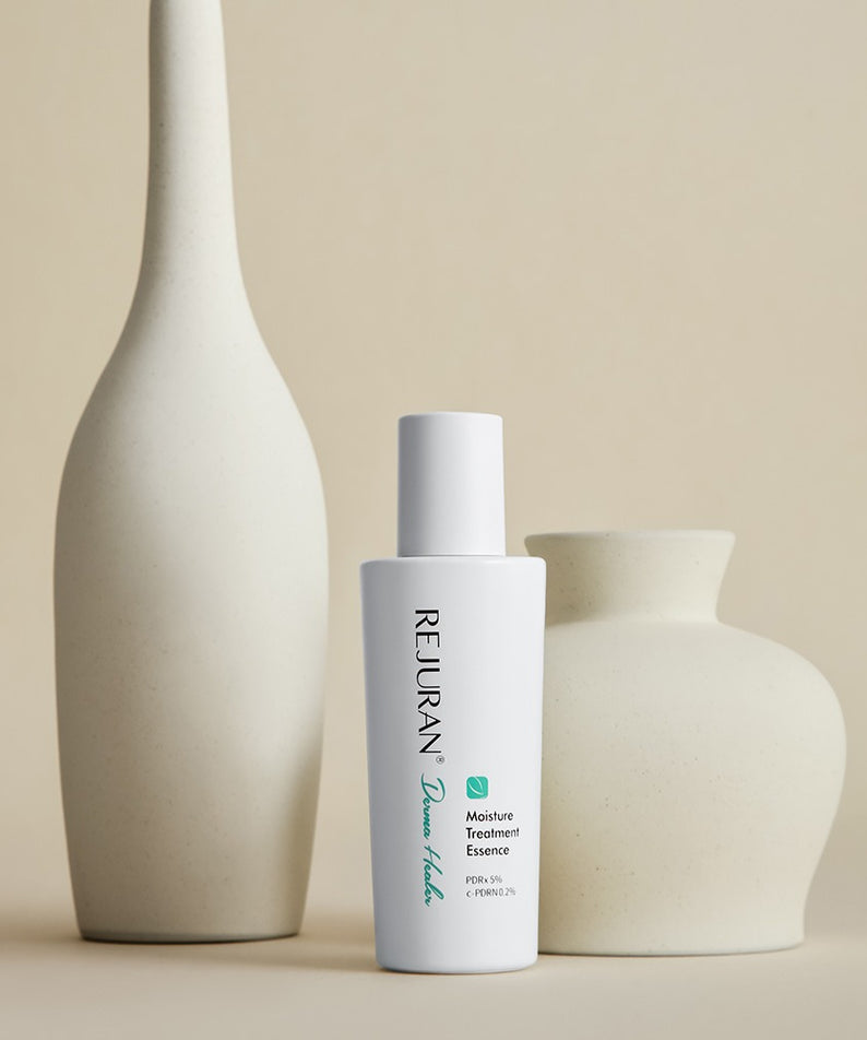 REJURAN Derma Healer Moisture Treatment Essence 70g - Élixir hydratant pour la peau, bouteille de 70g posée entre des vases.