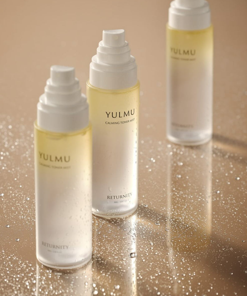 RETURNITY Yulmu Calming Toner Mist 100ml, bouteilles sur fond beige avec brume/particules, marque RETURNITY visible