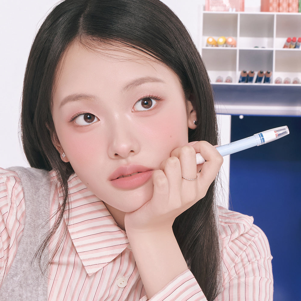 ROMAND  Blurpy Lip Crayon, maquillage lèvres : la femme tient le crayon près du visage, décor cosmétiques en arrière-plan
