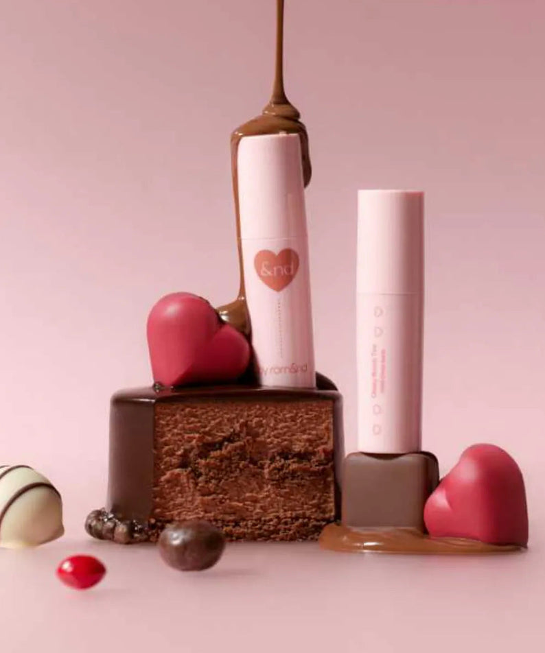 ROMAND  Glassy Bomb Tint de marque ROMAND, flacon rose brillant sur fond pastel avec éléments déco.
