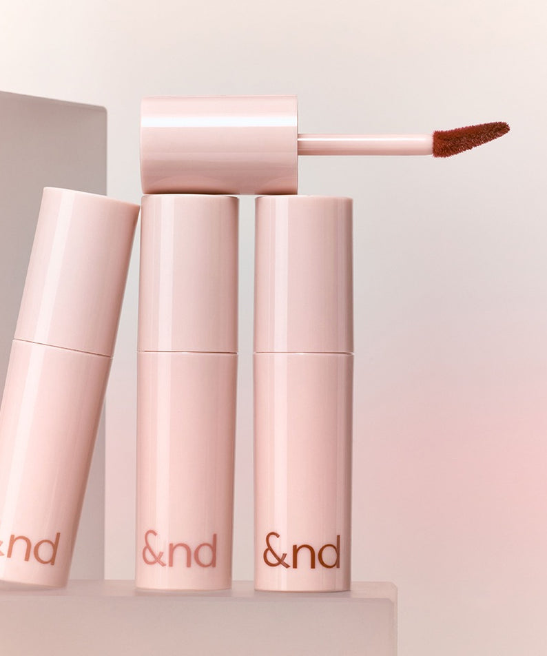ROMAND  Glassy Bomb Tint de la marque ROMAND, visuel en tube rose et applicateur bourgogne sur fond lumineux