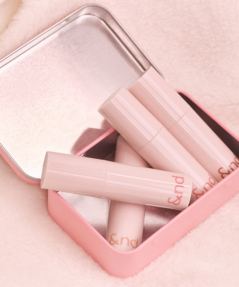 ROMAND  Glassy Bomb Tint, tube de gloss rose dans son étui, sur fond tissu, marque ROMAND, visuel beauté.