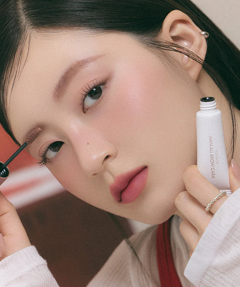 ROMAND  Hanol Brow Cara Single Item, maquillage sourcils sur modèle, tube en main, fond studio.