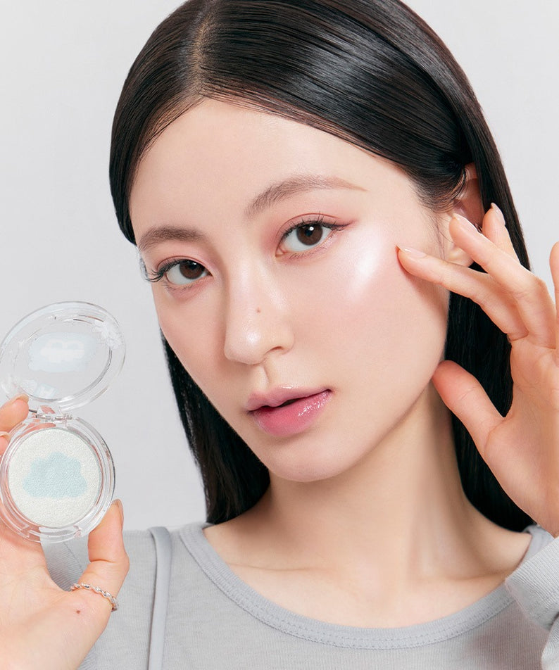 ROMAND x Joanne Friends Dual Jelly Highlighter : produit de la marque ROMAND sur peau maquillée, duo gelée lumineuse, main tenant le boîtier.