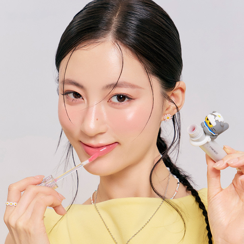 ROMAND x Joanne Friends Glasting Color Gloss, femme souriante applique le gloss, partenariat ROMAND, fond clair