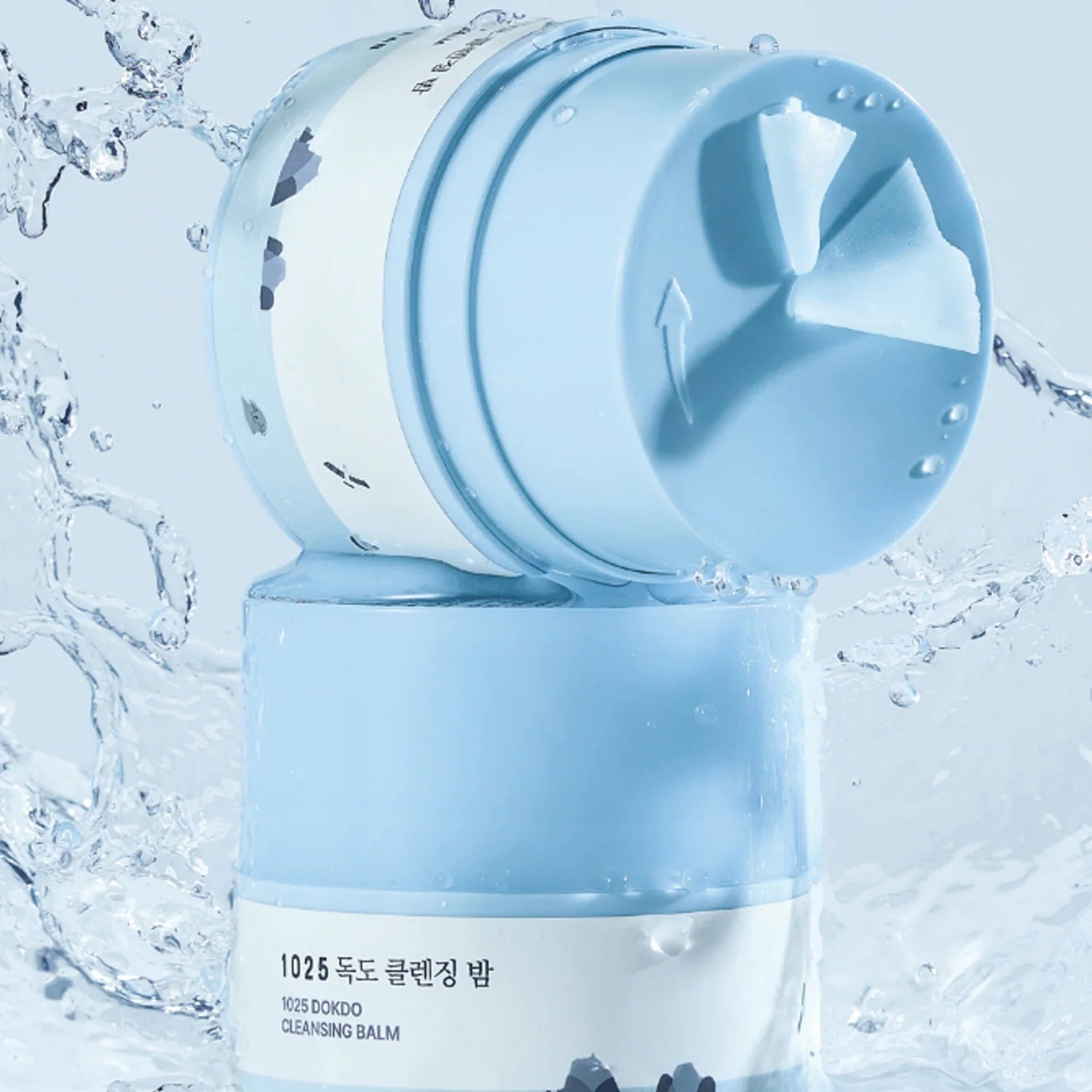 ROUND LAB 1025 Dokdo Cleansing Balm 50ml de Round Lab, baume nettoyant dans un contexte aquatique bleu, gouttes d’eau.