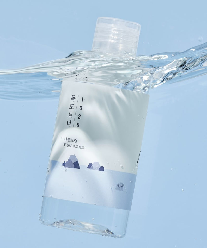 ROUND LAB 1025 Dokdo Toner flottant dans l'eau, produit de soin pour la peau en bouteilles minimalistes design avec étiquette esthétique coréenne.