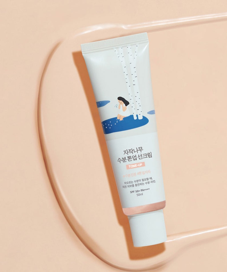Crème solaire ROUND LAB Birch Juice Moisturizing Tone-up Sunscreen 50ml sur fond beige, protection et hydratation.