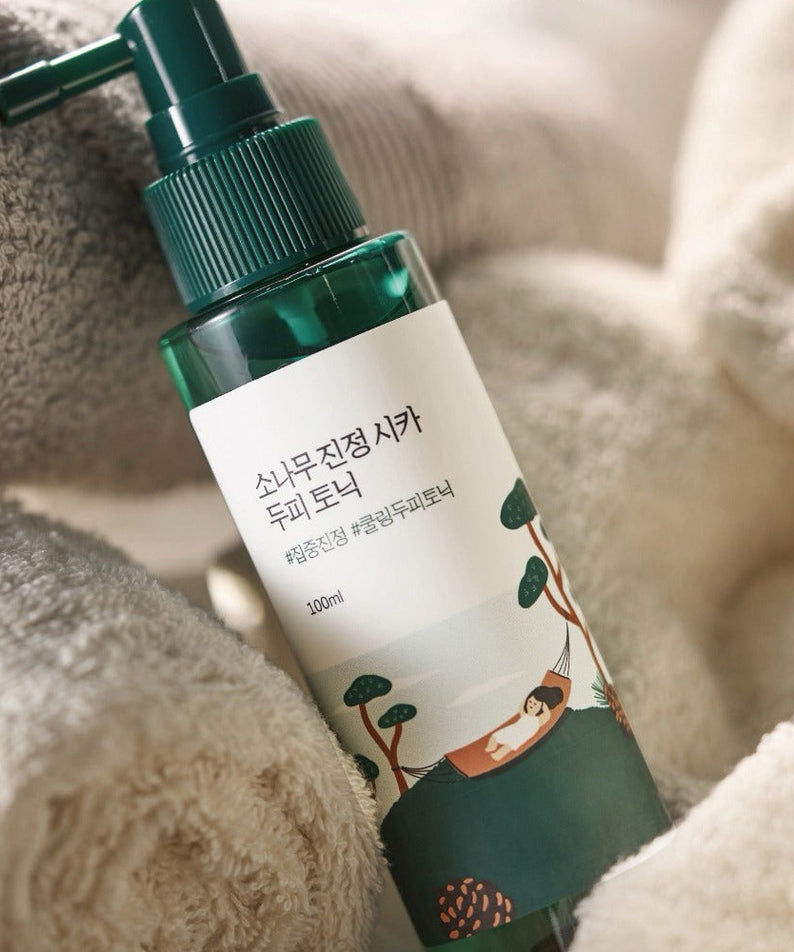 ROUND LAB  Pine Calming Cica Hair Tonic 100ml sur serviette douce, marque ROUND LAB, contexte spa à la maison