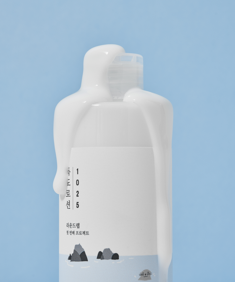 Bouteille de ROUND LAB 1025 Dokdo Lotion 400ml avec texture lisse et étiquette minimaliste sur fond bleu.