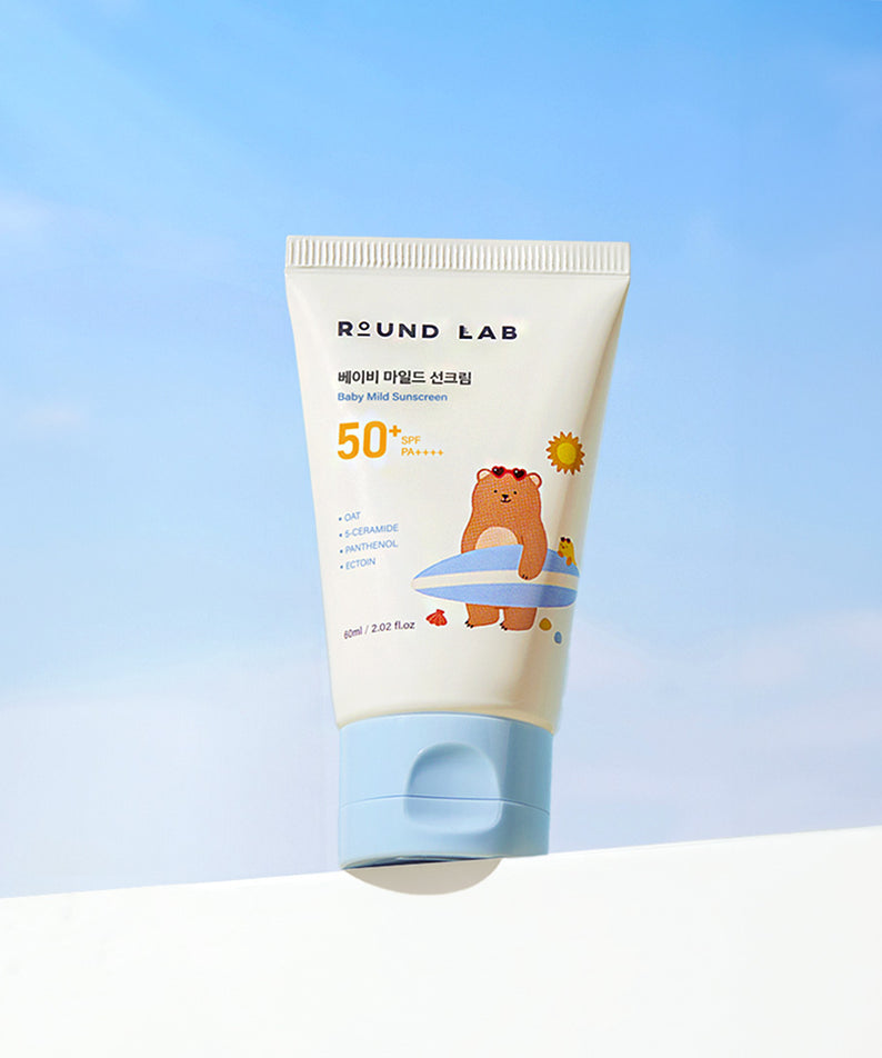 Crème solaire douce ROUND LAB Baby Mild Sun Cream 60ml pour bébé, protection SPF50, tube illustré d'un ours, ciel bleu en arrière-plan.