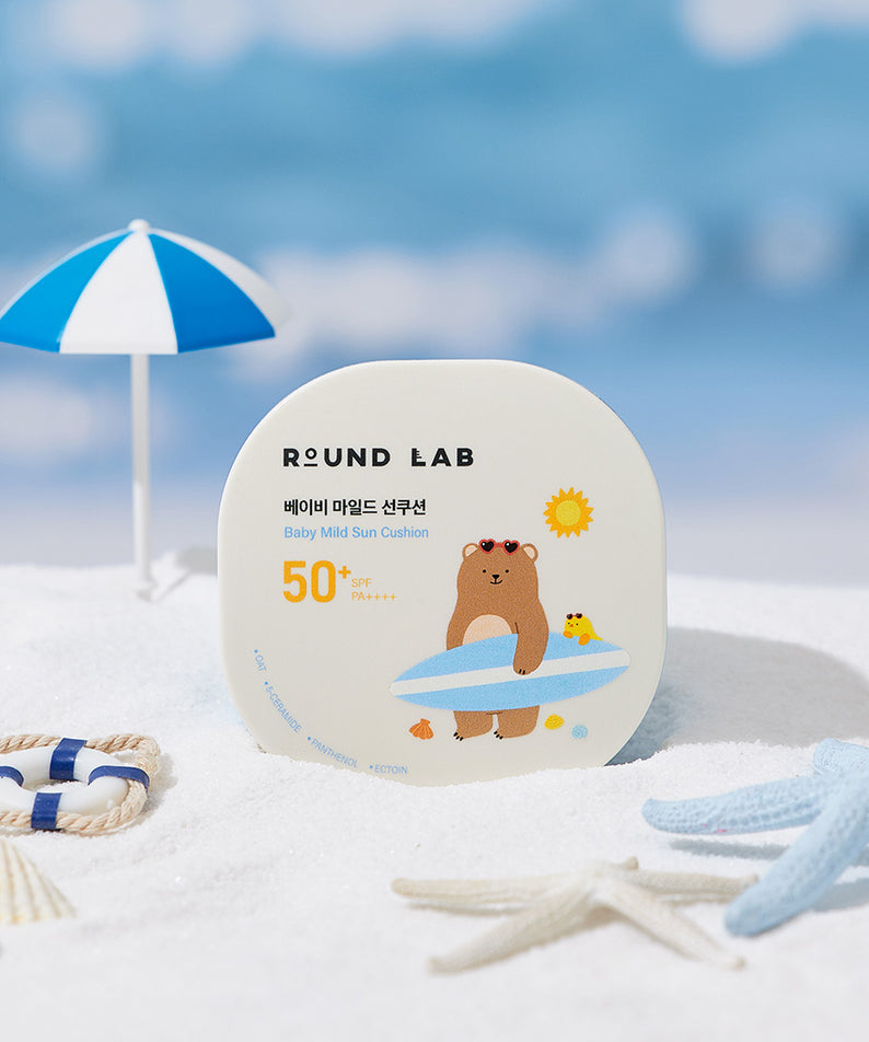 Coussin solaire doux pour bébé ROUND LAB Baby Mild Sun Cushion 16g, protection solaire FPS 50 avec design d'ours mignon sur la plage.