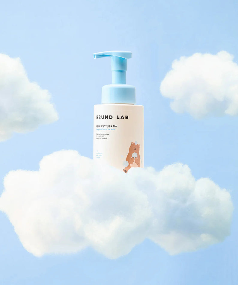 ROUND LAB Baby Mild Top To Toe Wash 300ml entre des nuages, flacon bleu, produit doux pour bébé.