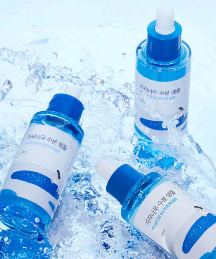 Bouteilles de ROUND LAB Birch Moisture Ampoule 50ml sur fond aquatique rafraîchissant.