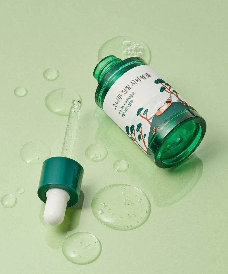 Flacon de ROUND LAB Pine Calming Cica Ampoule 30ml sur fond vert, idéal pour apaiser la peau sensible avec extrait de pin et cica.