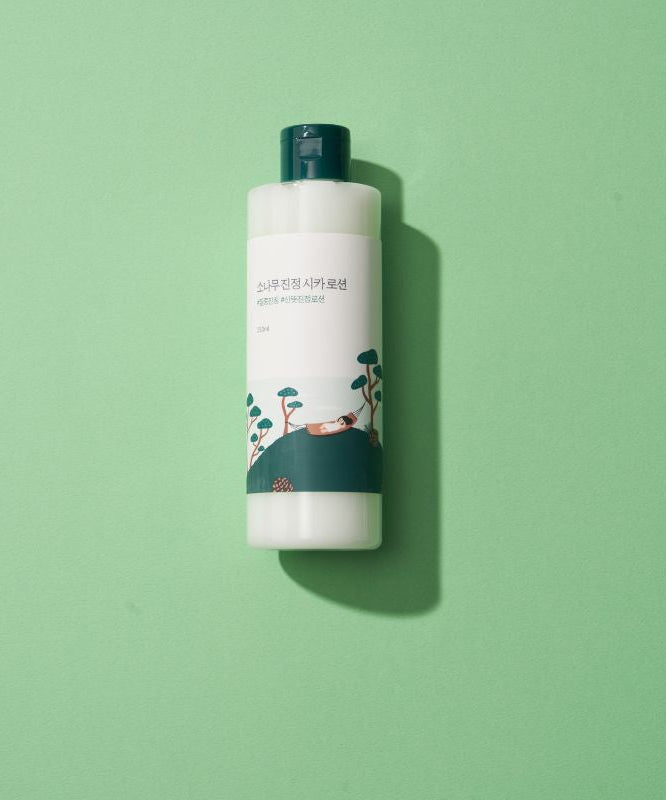 Bouteille de ROUND LAB Pine Calming Cica Lotion 250ml sur fond vert.