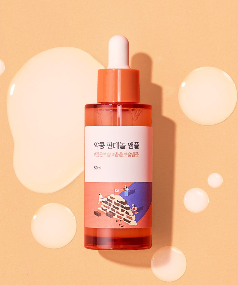 ROUND LAB Pine Calming Cica Ampoule 30ml posée sur fond beige avec du liquide autour, mettant en valeur un design apaisant.