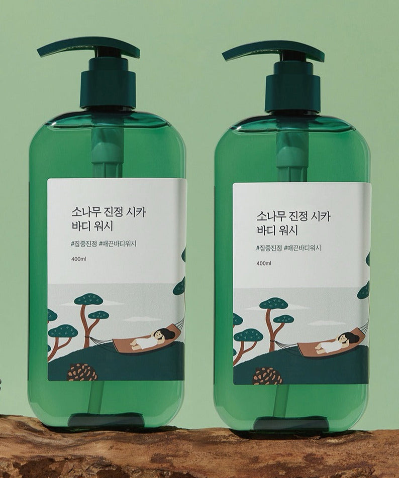 ROUND LAB Pine Calming Cica Body Wash 400ml - Deux flacons verts sur un fond vert avec une illustration relaxante.