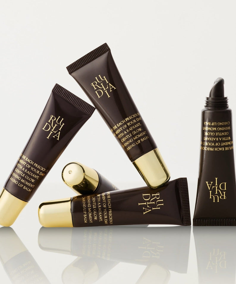 RULIDIA Shining Moment Caring Lip Balm 8g, tubes marron et or sur fond clair, marque RULIDIA, visuel promo.