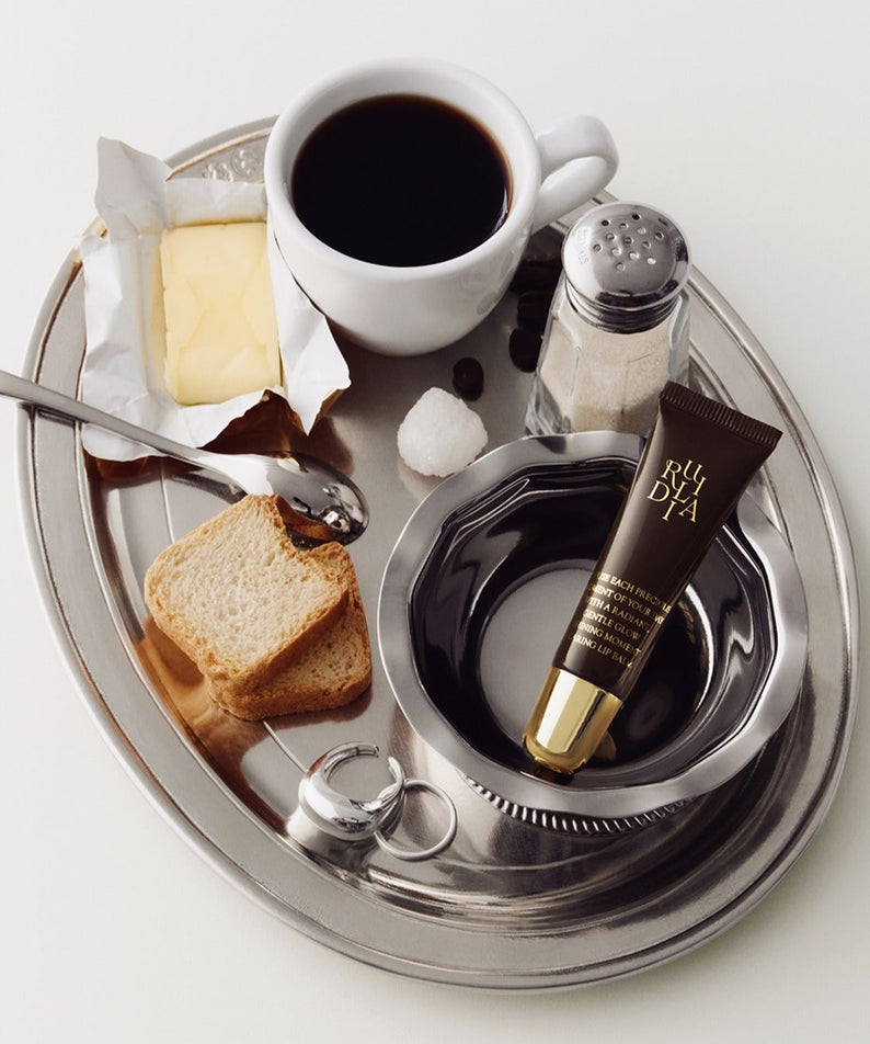 RULIDIA Shining Moment Caring Lip Balm 8g, tube élégant sur plateau avec accessoires beauté, style photo produit.