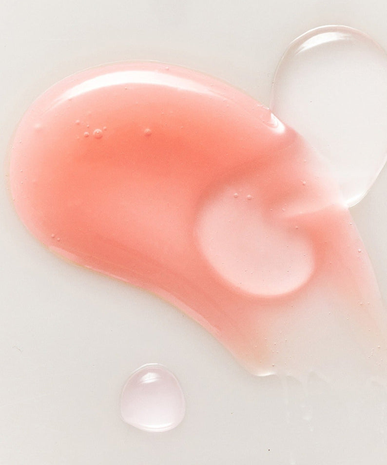 RULIDIA Shining Moment Caring Lip Balm 8g : baume luisant à texture rose, gouttes et produit en gros plan sur fond clair.