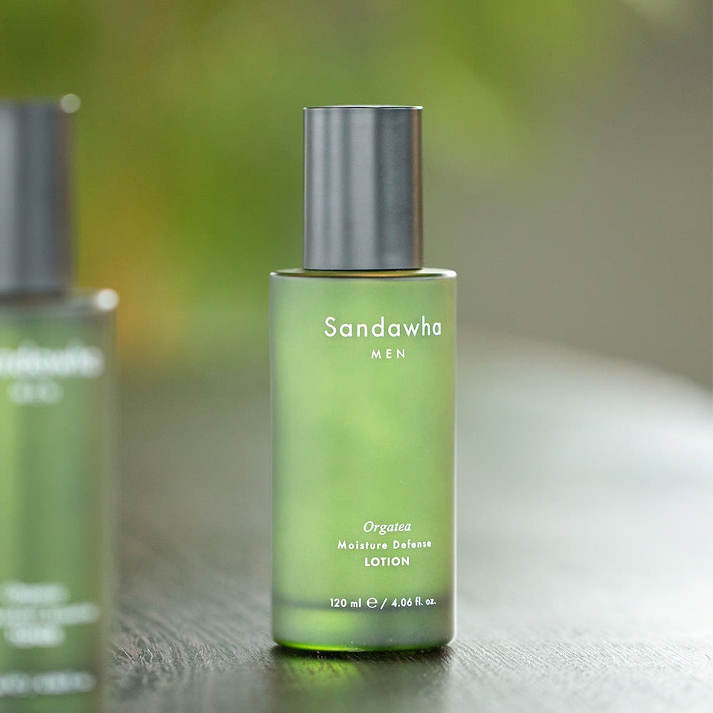 SANDAWHA For Men Orgatea Moiture Defense Lotion 120ml, flacon vert sur table, arrière-plan flou, photo produit en studio.