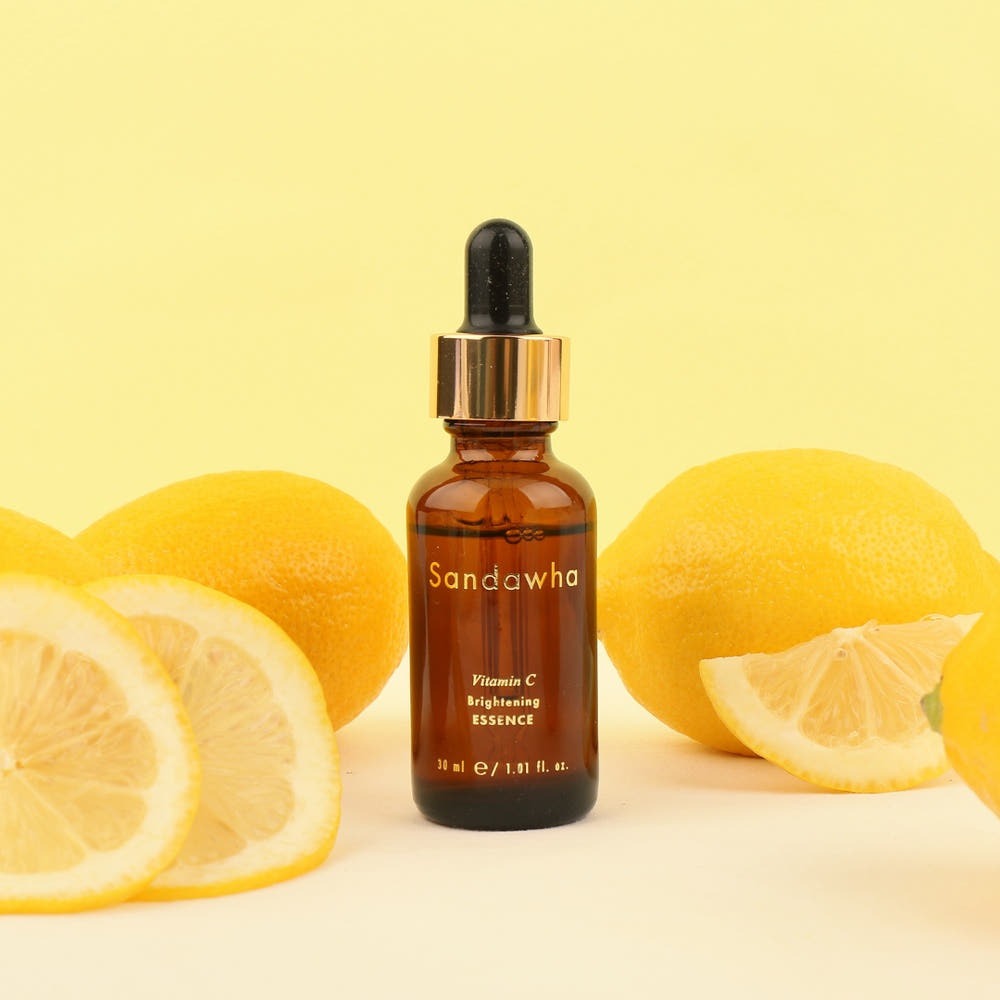 SANDAWHA Vitamin C Whitening Essence 30ml, flacon sur fond jaune avec citrons, mise en scène beauté
